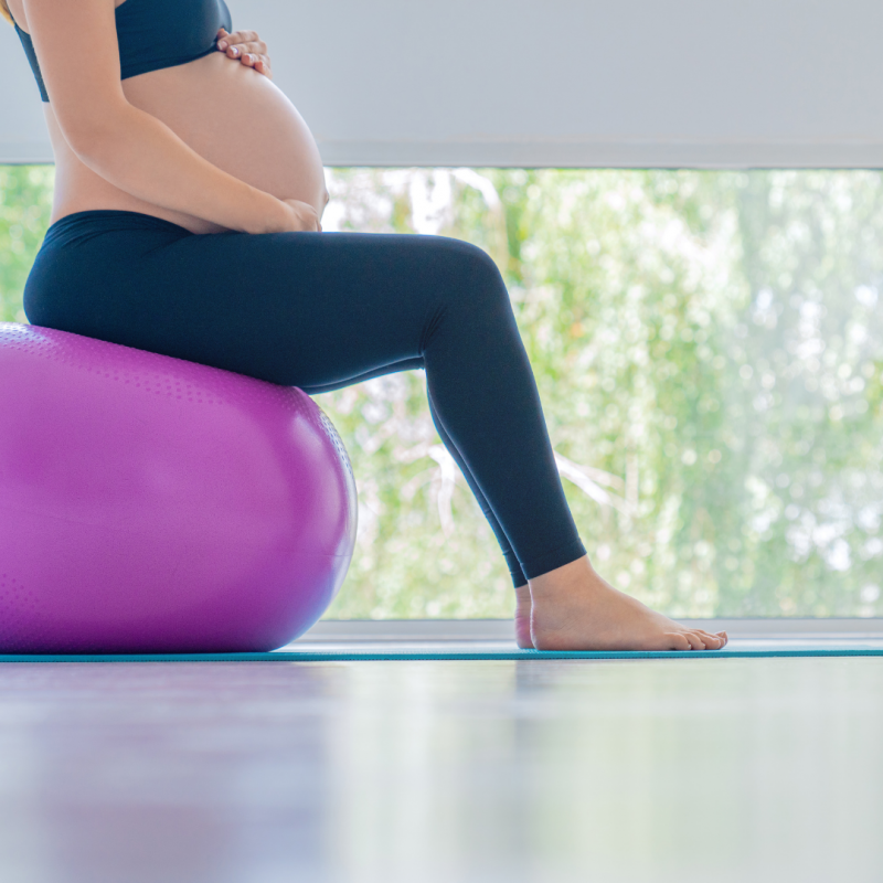 schwangere Frau sitzt auf einem Gymnastikball