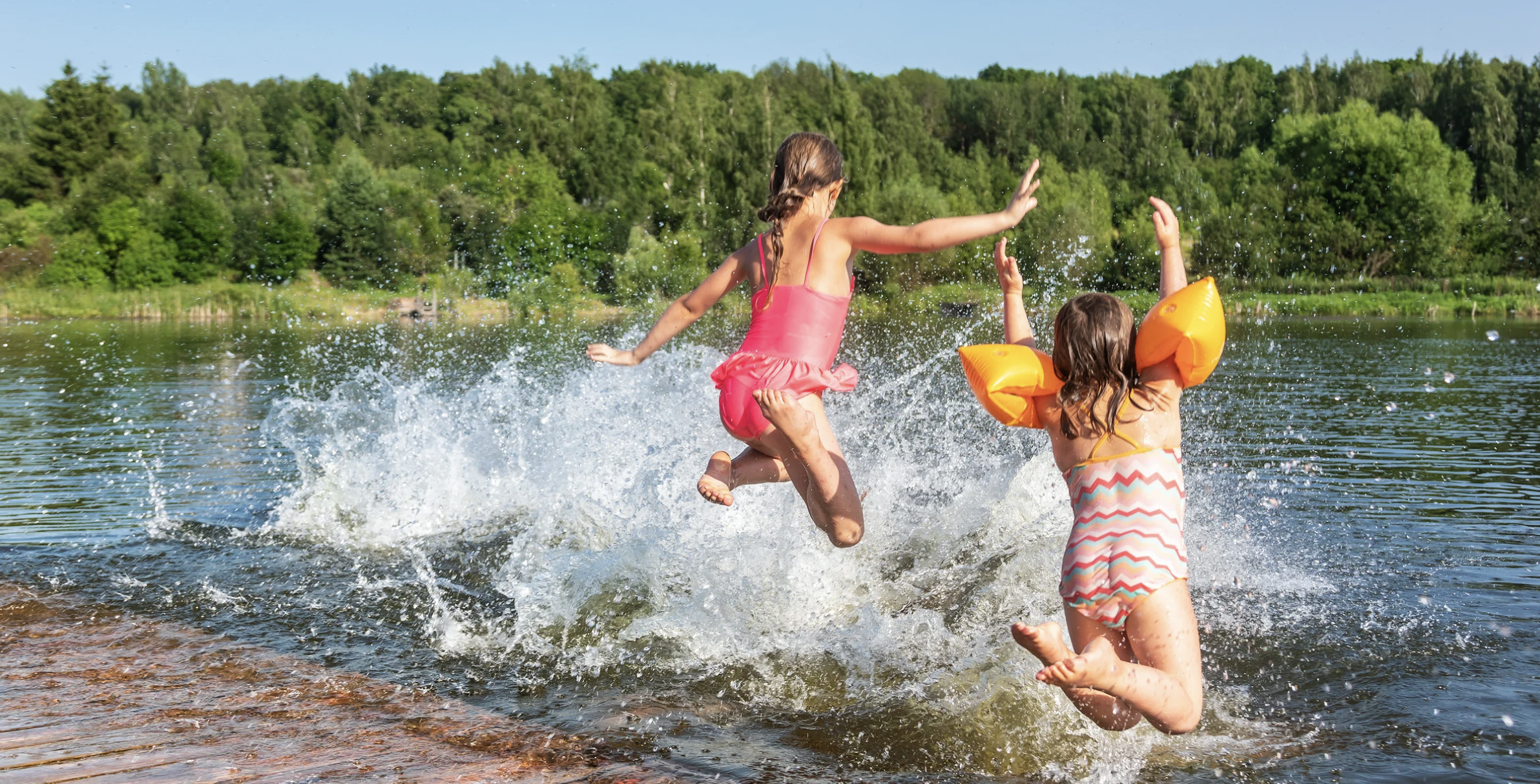 Kinder springen in einen See.